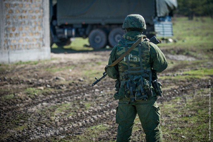 Một lính có vũ trang đứng gác cạnh bãi tập kết xe cơ giới