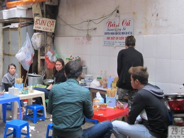 4. Bún cá Sâm Cây Si (ngõ Trung Yên, từ Đinh Liệt rẽ vào) Cái tên "Sâm cây si" cũng bắt nguồn từ chỗ bán hàng nằm đúng khúc cua của ngõ, bên cạnh một cây si, còn cô chủ hàng tên là Sâm. Bên ngoài quán trông hơi nhếch nhác vì nằm ở ngõ phố đông xe đi lại.