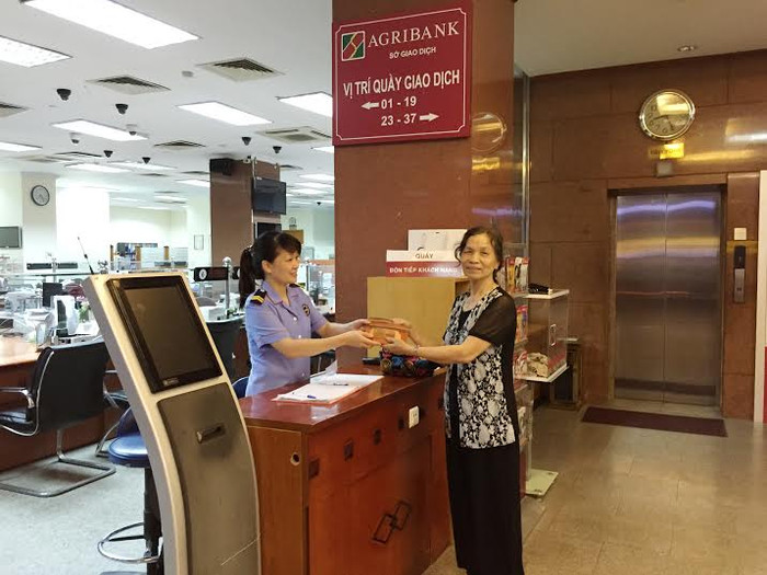 Bảo vệ Agribank trao trả ví tiền cho bà Vũ Thị Thâu.