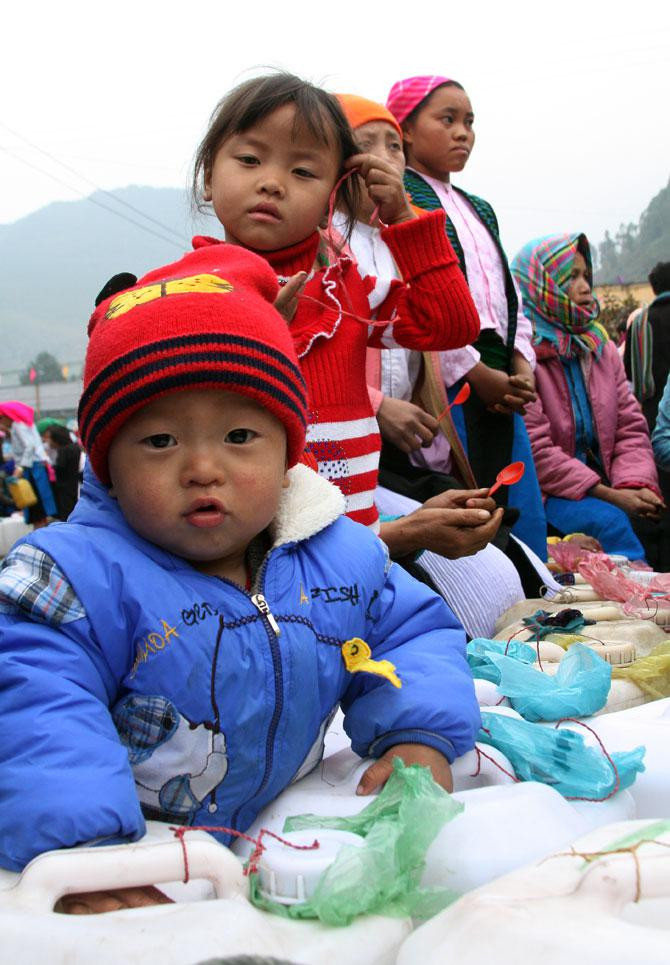 Ngoài việc gùi rượu trên lưng đến chợ, họ còn dắt theo cả những em bé đi cùng. Có lẽ với những em bé này, mỗi lần được đến chợ cùng mẹ là niềm vui bởi các em được gặp nhiều người và được ăn quà. Ngoài việc gùi rượu trên lưng đến chợ, họ còn dắt theo cả những em bé đi cùng. Có lẽ với những em bé này, mỗi lần được đến chợ cùng mẹ là niềm vui bởi các em được gặp nhiều người và được ăn quà.