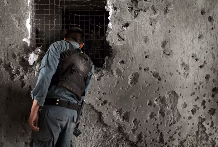 Một cảnh sát Afghanistan quan sát các thi thể của phiến quân trong ngôi nhà mà chúng đã chiếm đóng để tấn công sứ quán Mỹ ở Kabul.