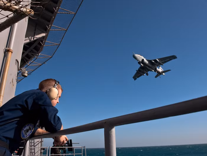 Vịnh A Rập:Một quân nhân đang quan sát mặt nước biển từ tàu sân bay USS John C. Stennis (CVN 74), khi chiếc EA-6B Prowler thuộc phi đội tác chiến điện tử đang bay ngang qua chiếc siêu hạm C. Stennis.
