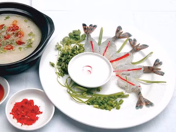 Cháo gần chín, bỏ thịt tôm vào (nếu muốn cháo ngọt hơn có thể cho thêm nghêu sống, bỏ vào nồi cháo trước khi cho thịt tôm) và cho gia vị, nêm nếm vừa ăn. Nhắc cháo xuống, cho hành lá xắt nhỏ, ngò, cho ít tiêu xay vào, ăn nóng. Lúc này bạn đã có nồi cháo thơm ngậy với màu đỏ của thịt tôm, màu vàng nhẹ của mỡ phi, màu xanh của hành ngò.