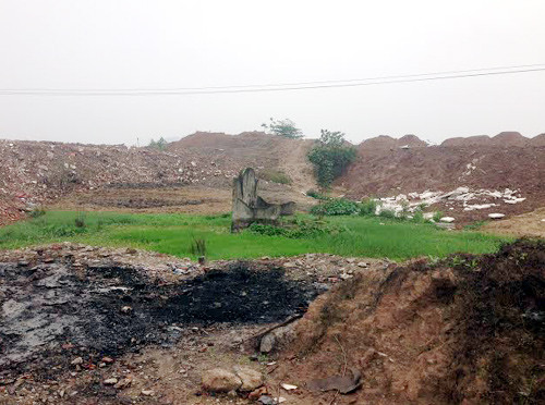 Một ngôi mộ có nguy cơ bị san lấp giữa một khối đất khổng lồ tại một dự án đang triển khai giải toản mặt bằng.