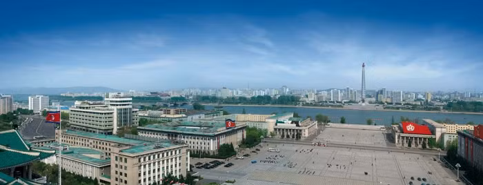 Ảnh chụp Giảng đường Nghiên cứu Nhân dân lớn, Quảng trường Kim Il-Sung và có cả Ngọn đuốc đỏ ở bên kia sông.