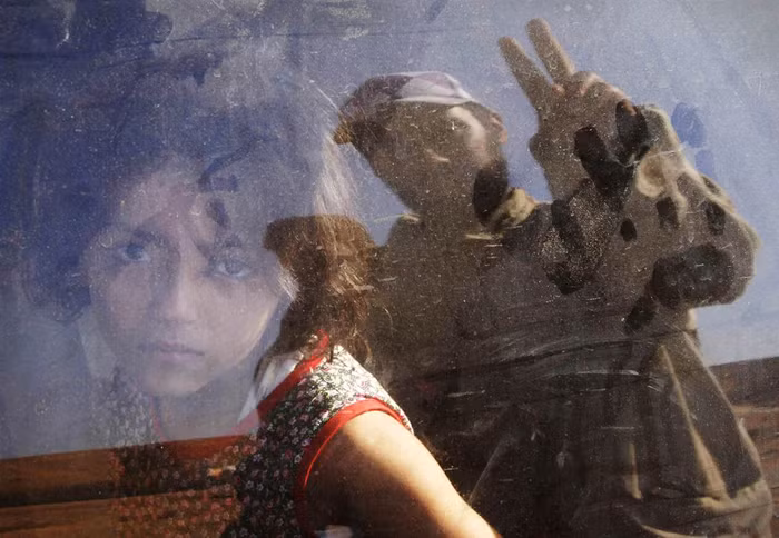 Một tay súng phiến quân đang giơ biểu tượng chiến thắng vẫy chào một gia đình người chạy nạn ở Bani Walid, Libya khi lực lượng đối lập tấn công vào thành trình của Gaddafi (ảnh chụp ngày 14/9/2011).