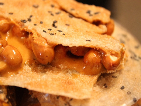 Bánh cu đơ là sự kết hợp giữa cái giòn của vỏ lớp bánh đa bên ngoài, cái ngọt dẻo cả lớp mật bên trong hòa cùng cái béo bùi của lạc rang và thoang thoảng hương thơm của gừng tươi. Ảnh: lamsao.com