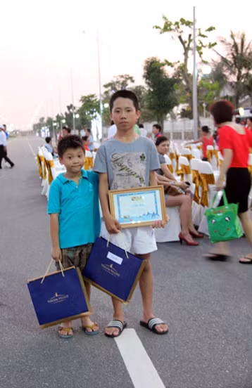 Sau nửa ngày tham gia tranh tài sôi nổi trên đường đua xanh, các vận động viên nhí sung sướng ra về với những phần thưởng trĩu tay… Bé Vương Minh Phú, 5 tuổi (bên trái - nhà tại đường Hoa Phượng) cười toét miệng khoe: “Con được giải nhất bơi sải đấy. Ở đây được học bơi, học tennis, được đi học ở trường quốc tế BVIS nên con thích Vincom Village lắm”.