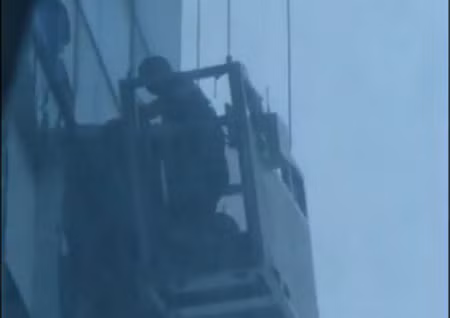 Các công nhân lau kính đang được đưa ra khỏi lồng sắt. Ảnh chụp từ clip.