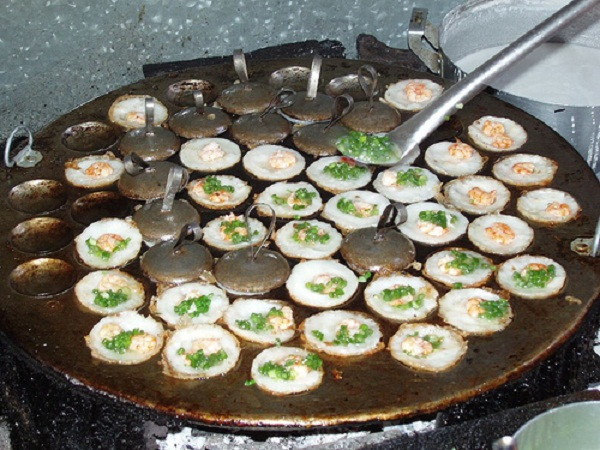 Bột bánh gồm gạo xay bột ớt, gạo nấu thành cơm và làm bún để nguội rồi xay đặc. Bột sau khi xay nêm các loại gia vị như muối, đường, bột ngọt cho vừa ăn. Đánh trứng gà trộn đều vào bột cho bánh có độ xốp. Nước dừa quấy đều, thêm ít bột nghệ để bánh có mà vàng đẹp. Sau đó cho hành lá băm nhỏ và tiêu xay nhuyễn quây đều. Ảnh: Ngoisao.net.