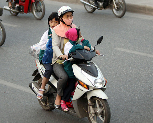 Đưa con đi học (Ảnh: TTXVN). Đưa con đi học (Ảnh: TTXVN).