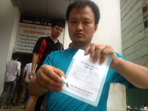 Anh Lam và lọ thuốc còn thừa sau khi tiêm cho con trai mình.