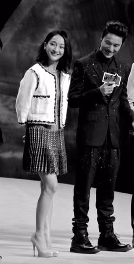 Châu Tấn mặc áo vải thô màu trắng kết hợp với váy xếp li lưng cao, phối hợp màu trắng cùng màu ghi thanh nhã, lịch sự.