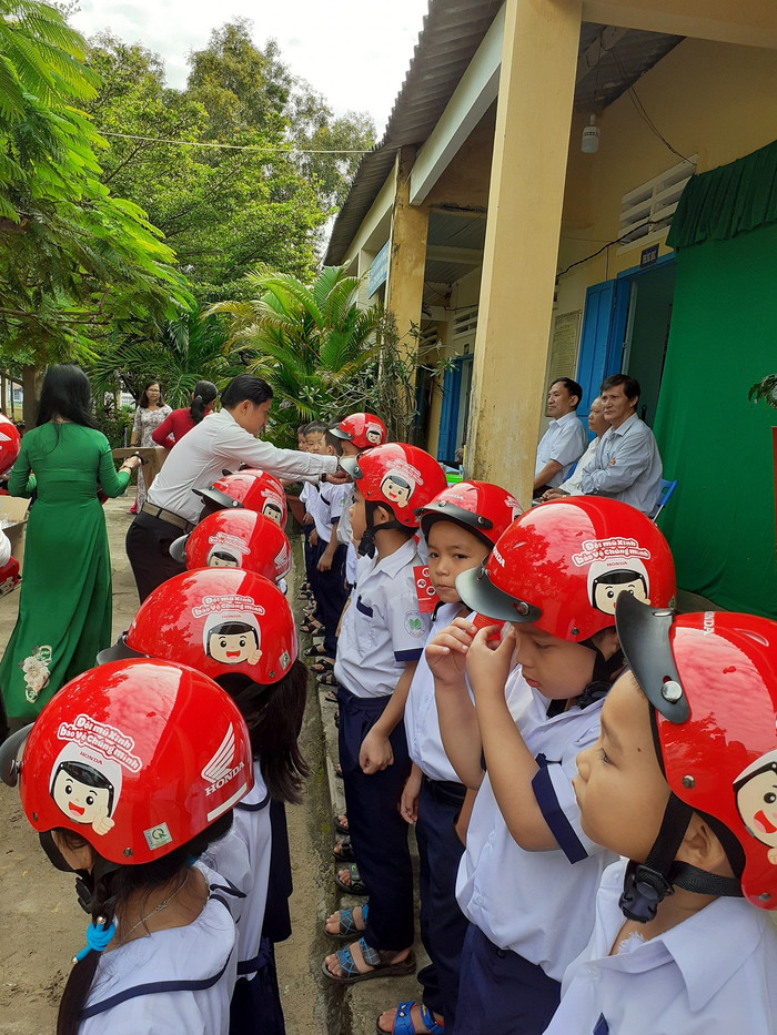 Học sinh lớp 1 nhận nón bảo hiểm trong lễ khai giảng (Ảnh Phan Tuyết)