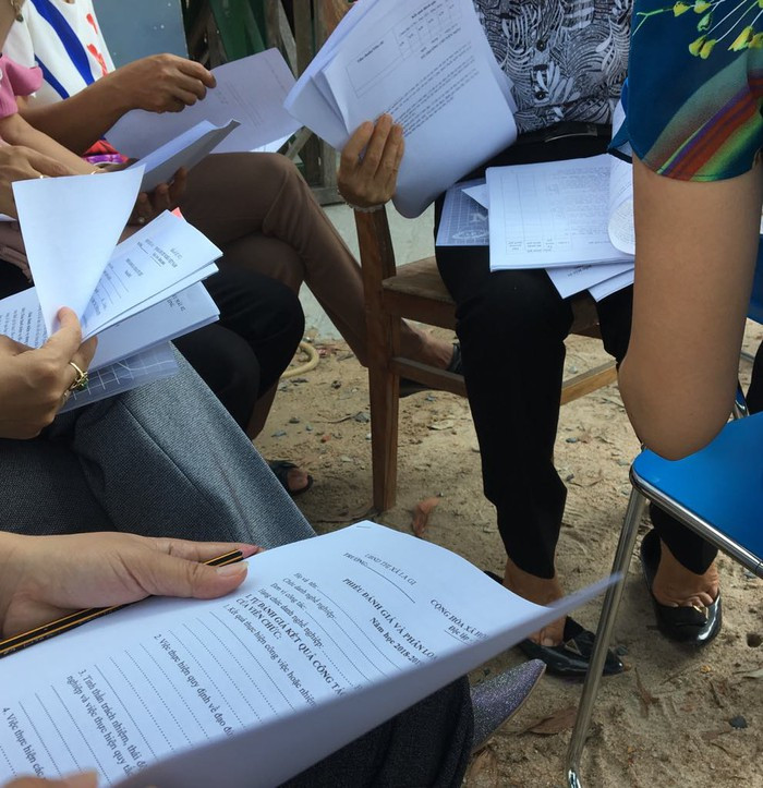 Giáo viên nhận hàng xấp phiếu nhận xét đánh giá (Ảnh tác giả)