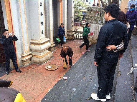 Cụ Đãi lom khom quét gạo rơi tại cổng đền. (Ảnh: Đào Tiến Vinh) Cụ Đãi lom khom quét gạo rơi tại cổng đền. (Ảnh: Đào Tiến Vinh)