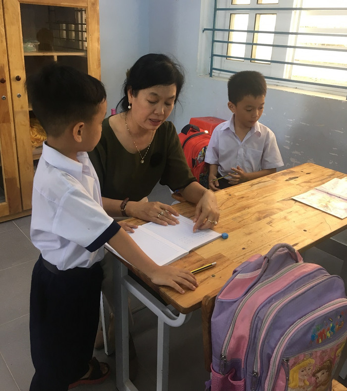 Mỗi giờ ra chơi giáo viên lớp Một thường ngồi kèm cho học sinh yếu thế này (Ảnh tác giả)