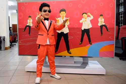 Trong suốt buổi giao lưu, cậu bé luôn đeo kính đen, mặc bộ comple hồng, diện giầy trắng, cổ thắt nơ điệu nghệ.