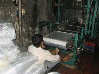 Công nhân điều khiển máy thổi túi nilon miệt mài Công nhân điều khiển máy thổi túi nilon miệt mài