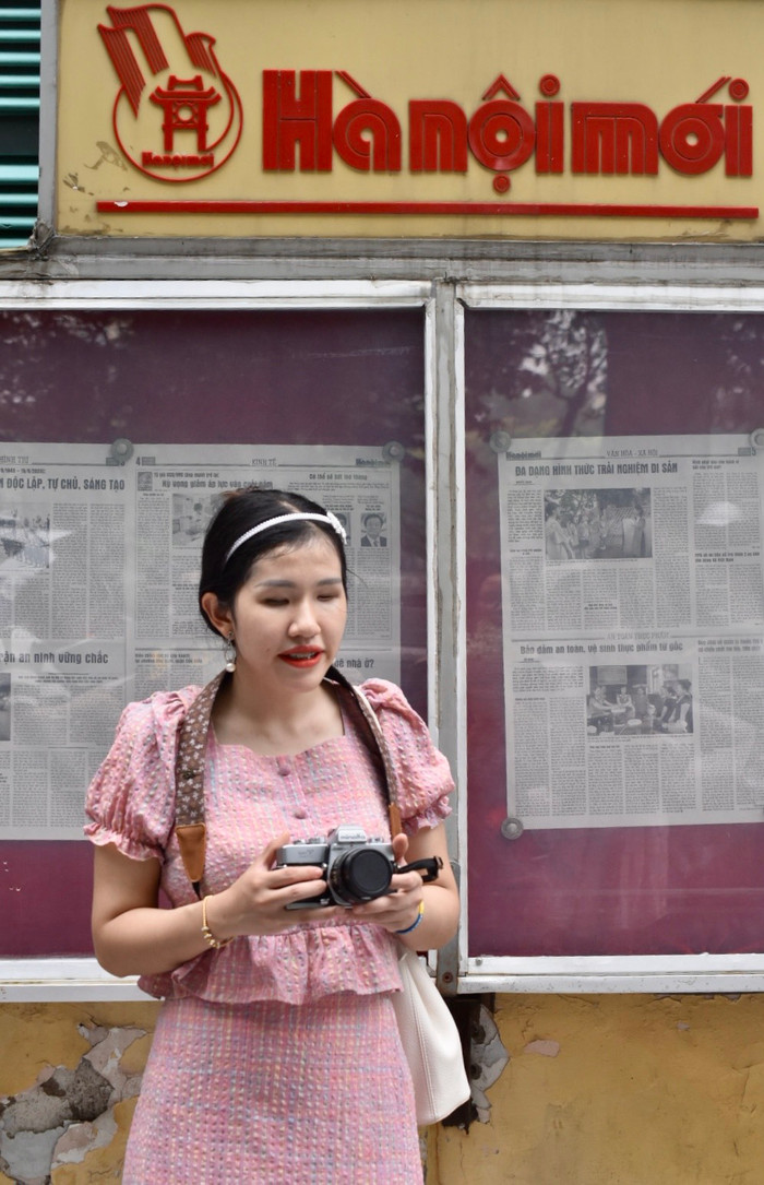 Hải Anh hi vọng các bạn trẻ đừng sợ hãi thất bại. Ảnh: NVCC. ảnh này xinh lắm ạ. cô gái trong set áo váy hồng, vai đeo balo và túi xách màu trắng kem, tóc cột gọn, đeo bờm mảnh màu trắng, 2 tay cầm máy ảnh analog, miệng cười tự nhiên. cô gái đứng chếch về bên trái tấm ảnh 1 .jpg
