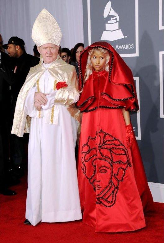 Chiếc váy đỏ đính nhiều hạt cườm màu đen với găng tay satin đỏ là thiết kế của Versace. Nicki Minaj thực sự "chơi trội" khi khoác tay "Đức Giáo Hoàng" đi trên thảm đỏ.