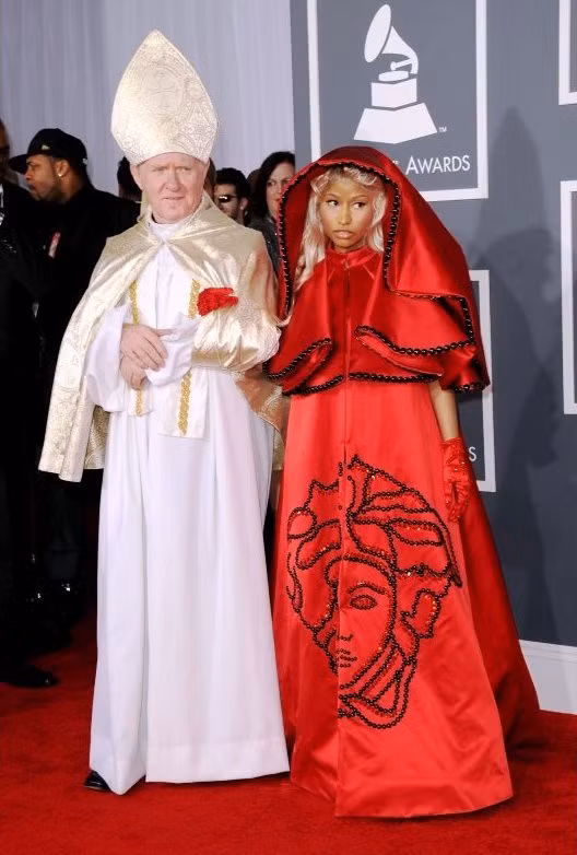 Chiếc váy đỏ đính nhiều hạt cườm màu đen với găng tay satin đỏ là thiết kế của Versace. Nicki Minaj thực sự "chơi trội" khi khoác tay "Đức Giáo Hoàng" đi trên thảm đỏ. Chiếc váy đỏ đính nhiều hạt cườm màu đen với găng tay satin đỏ là thiết kế của Versace. Nicki Minaj thực sự "chơi trội" khi khoác tay "Đức Giáo Hoàng" đi trên thảm đỏ.