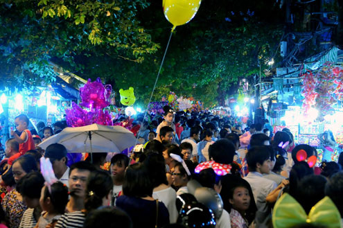 Tối 10/9, chợ đồ chơi Hàng Mã, Hàng Lược, Lương Văn Can, Hàng Đường... đông nghẹt người dạo chơi, tham quan, mua sắm. Trước đêm trung thu 2 ngày, dòng người chen lấn mua đồ chơi. Hai cô gái trẻ đứng giữa đoàn người qua lại ngắm nghía mình qua chiếc gương. Các cửa hàng bày hàng tràn lan ra đường làm thu hẹp không gian thưởng ngoạn của người chơi. Giải pháp cho bé ngồi trên vai là cách chống chen bẹp người của nhiều ông bố. Nạn bắn súng bong bóng xà phòng vào người đi đường vẫn tiếp diễn. Ôtô len vào nơi này cũng gặp khó khăn. Tài xế phải thò đầu ra nhờ mọi người tránh đường. Nhiều hàng bày bán lấn chiếm lòng lề đường khiến lực lượng bảo vệ phải liên tục làm việc. Và đội quân bán rong lại cầm ghế, bê hàng chạy sang chỗ khác. Những chiếc mặt nạ quái đản lại xuất hiện. Tối 10/9, chợ đồ chơi Hàng Mã, Hàng Lược, Lương Văn Can, Hàng Đường... đông nghẹt người dạo chơi, tham quan, mua sắm. Trước đêm trung thu 2 ngày, dòng người chen lấn mua đồ chơi. Hai cô gái trẻ đứng giữa đoàn người qua lại ngắm nghía mình qua chiếc gương. Các cửa hàng bày hàng tràn lan ra đường làm thu hẹp không gian thưởng ngoạn của người chơi. Giải pháp cho bé ngồi trên vai là cách chống chen bẹp người của nhiều ông bố. Nạn bắn súng bong bóng xà phòng vào người đi đường vẫn tiếp diễn. Ôtô len vào nơi này cũng gặp khó khăn. Tài xế phải thò đầu ra nhờ mọi người tránh đường. Nhiều hàng bày bán lấn chiếm lòng lề đường khiến lực lượng bảo vệ phải liên tục làm việc. Và đội quân bán rong lại cầm ghế, bê hàng chạy sang chỗ khác. Những chiếc mặt nạ quái đản lại xuất hiện.