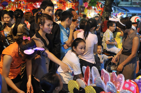 Tối 10/9, chợ đồ chơi Hàng Mã, Hàng Lược, Lương Văn Can, Hàng Đường... đông nghẹt người dạo chơi, tham quan, mua sắm. Trước đêm trung thu 2 ngày, dòng người chen lấn mua đồ chơi. Hai cô gái trẻ đứng giữa đoàn người qua lại ngắm nghía mình qua chiếc gương. Các cửa hàng bày hàng tràn lan ra đường làm thu hẹp không gian thưởng ngoạn của người chơi. Giải pháp cho bé ngồi trên vai là cách chống chen bẹp người của nhiều ông bố. Nạn bắn súng bong bóng xà phòng vào người đi đường vẫn tiếp diễn. Ôtô len vào nơi này cũng gặp khó khăn. Tài xế phải thò đầu ra nhờ mọi người tránh đường. Nhiều hàng bày bán lấn chiếm lòng lề đường khiến lực lượng bảo vệ phải liên tục làm việc. Và đội quân bán rong lại cầm ghế, bê hàng chạy sang chỗ khác. Những chiếc mặt nạ quái đản lại xuất hiện. Tối 10/9, chợ đồ chơi Hàng Mã, Hàng Lược, Lương Văn Can, Hàng Đường... đông nghẹt người dạo chơi, tham quan, mua sắm. Trước đêm trung thu 2 ngày, dòng người chen lấn mua đồ chơi. Hai cô gái trẻ đứng giữa đoàn người qua lại ngắm nghía mình qua chiếc gương. Các cửa hàng bày hàng tràn lan ra đường làm thu hẹp không gian thưởng ngoạn của người chơi. Giải pháp cho bé ngồi trên vai là cách chống chen bẹp người của nhiều ông bố. Nạn bắn súng bong bóng xà phòng vào người đi đường vẫn tiếp diễn. Ôtô len vào nơi này cũng gặp khó khăn. Tài xế phải thò đầu ra nhờ mọi người tránh đường. Nhiều hàng bày bán lấn chiếm lòng lề đường khiến lực lượng bảo vệ phải liên tục làm việc. Và đội quân bán rong lại cầm ghế, bê hàng chạy sang chỗ khác. Những chiếc mặt nạ quái đản lại xuất hiện.