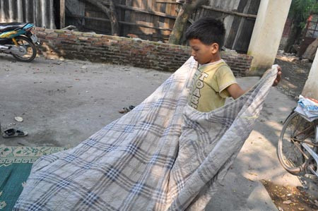 Cháu Quốc Anh vội vàng gấp chăn khi thấy người lạ đến.