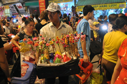 Tối 10/9, chợ đồ chơi Hàng Mã, Hàng Lược, Lương Văn Can, Hàng Đường... đông nghẹt người dạo chơi, tham quan, mua sắm. Trước đêm trung thu 2 ngày, dòng người chen lấn mua đồ chơi. Hai cô gái trẻ đứng giữa đoàn người qua lại ngắm nghía mình qua chiếc gương. Các cửa hàng bày hàng tràn lan ra đường làm thu hẹp không gian thưởng ngoạn của người chơi. Giải pháp cho bé ngồi trên vai là cách chống chen bẹp người của nhiều ông bố. Nạn bắn súng bong bóng xà phòng vào người đi đường vẫn tiếp diễn. Ôtô len vào nơi này cũng gặp khó khăn. Tài xế phải thò đầu ra nhờ mọi người tránh đường. Nhiều hàng bày bán lấn chiếm lòng lề đường khiến lực lượng bảo vệ phải liên tục làm việc. Và đội quân bán rong lại cầm ghế, bê hàng chạy sang chỗ khác. Những chiếc mặt nạ quái đản lại xuất hiện. Tối 10/9, chợ đồ chơi Hàng Mã, Hàng Lược, Lương Văn Can, Hàng Đường... đông nghẹt người dạo chơi, tham quan, mua sắm. Trước đêm trung thu 2 ngày, dòng người chen lấn mua đồ chơi. Hai cô gái trẻ đứng giữa đoàn người qua lại ngắm nghía mình qua chiếc gương. Các cửa hàng bày hàng tràn lan ra đường làm thu hẹp không gian thưởng ngoạn của người chơi. Giải pháp cho bé ngồi trên vai là cách chống chen bẹp người của nhiều ông bố. Nạn bắn súng bong bóng xà phòng vào người đi đường vẫn tiếp diễn. Ôtô len vào nơi này cũng gặp khó khăn. Tài xế phải thò đầu ra nhờ mọi người tránh đường. Nhiều hàng bày bán lấn chiếm lòng lề đường khiến lực lượng bảo vệ phải liên tục làm việc. Và đội quân bán rong lại cầm ghế, bê hàng chạy sang chỗ khác. Những chiếc mặt nạ quái đản lại xuất hiện.