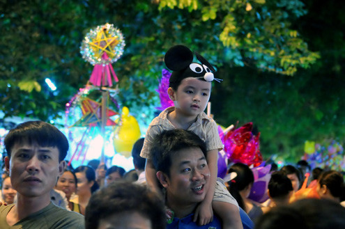 Tối 10/9, chợ đồ chơi Hàng Mã, Hàng Lược, Lương Văn Can, Hàng Đường... đông nghẹt người dạo chơi, tham quan, mua sắm. Trước đêm trung thu 2 ngày, dòng người chen lấn mua đồ chơi. Hai cô gái trẻ đứng giữa đoàn người qua lại ngắm nghía mình qua chiếc gương. Các cửa hàng bày hàng tràn lan ra đường làm thu hẹp không gian thưởng ngoạn của người chơi. Giải pháp cho bé ngồi trên vai là cách chống chen bẹp người của nhiều ông bố. Nạn bắn súng bong bóng xà phòng vào người đi đường vẫn tiếp diễn. Ôtô len vào nơi này cũng gặp khó khăn. Tài xế phải thò đầu ra nhờ mọi người tránh đường. Nhiều hàng bày bán lấn chiếm lòng lề đường khiến lực lượng bảo vệ phải liên tục làm việc. Và đội quân bán rong lại cầm ghế, bê hàng chạy sang chỗ khác. Những chiếc mặt nạ quái đản lại xuất hiện. Tối 10/9, chợ đồ chơi Hàng Mã, Hàng Lược, Lương Văn Can, Hàng Đường... đông nghẹt người dạo chơi, tham quan, mua sắm. Trước đêm trung thu 2 ngày, dòng người chen lấn mua đồ chơi. Hai cô gái trẻ đứng giữa đoàn người qua lại ngắm nghía mình qua chiếc gương. Các cửa hàng bày hàng tràn lan ra đường làm thu hẹp không gian thưởng ngoạn của người chơi. Giải pháp cho bé ngồi trên vai là cách chống chen bẹp người của nhiều ông bố. Nạn bắn súng bong bóng xà phòng vào người đi đường vẫn tiếp diễn. Ôtô len vào nơi này cũng gặp khó khăn. Tài xế phải thò đầu ra nhờ mọi người tránh đường. Nhiều hàng bày bán lấn chiếm lòng lề đường khiến lực lượng bảo vệ phải liên tục làm việc. Và đội quân bán rong lại cầm ghế, bê hàng chạy sang chỗ khác. Những chiếc mặt nạ quái đản lại xuất hiện.