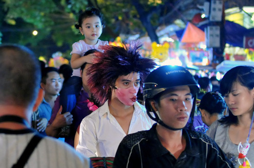 Tối 10/9, chợ đồ chơi Hàng Mã, Hàng Lược, Lương Văn Can, Hàng Đường... đông nghẹt người dạo chơi, tham quan, mua sắm. Trước đêm trung thu 2 ngày, dòng người chen lấn mua đồ chơi. Hai cô gái trẻ đứng giữa đoàn người qua lại ngắm nghía mình qua chiếc gương. Các cửa hàng bày hàng tràn lan ra đường làm thu hẹp không gian thưởng ngoạn của người chơi. Giải pháp cho bé ngồi trên vai là cách chống chen bẹp người của nhiều ông bố. Nạn bắn súng bong bóng xà phòng vào người đi đường vẫn tiếp diễn. Ôtô len vào nơi này cũng gặp khó khăn. Tài xế phải thò đầu ra nhờ mọi người tránh đường. Nhiều hàng bày bán lấn chiếm lòng lề đường khiến lực lượng bảo vệ phải liên tục làm việc. Và đội quân bán rong lại cầm ghế, bê hàng chạy sang chỗ khác. Những chiếc mặt nạ quái đản lại xuất hiện. Tối 10/9, chợ đồ chơi Hàng Mã, Hàng Lược, Lương Văn Can, Hàng Đường... đông nghẹt người dạo chơi, tham quan, mua sắm. Trước đêm trung thu 2 ngày, dòng người chen lấn mua đồ chơi. Hai cô gái trẻ đứng giữa đoàn người qua lại ngắm nghía mình qua chiếc gương. Các cửa hàng bày hàng tràn lan ra đường làm thu hẹp không gian thưởng ngoạn của người chơi. Giải pháp cho bé ngồi trên vai là cách chống chen bẹp người của nhiều ông bố. Nạn bắn súng bong bóng xà phòng vào người đi đường vẫn tiếp diễn. Ôtô len vào nơi này cũng gặp khó khăn. Tài xế phải thò đầu ra nhờ mọi người tránh đường. Nhiều hàng bày bán lấn chiếm lòng lề đường khiến lực lượng bảo vệ phải liên tục làm việc. Và đội quân bán rong lại cầm ghế, bê hàng chạy sang chỗ khác. Những chiếc mặt nạ quái đản lại xuất hiện.