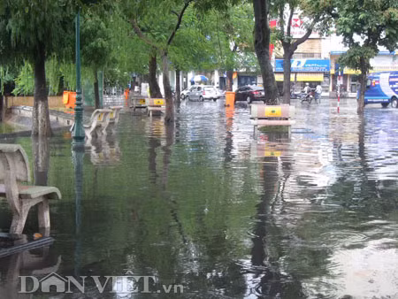 Dưới có hồ, còn phía trên lòng đường, vỉa hè cũng lại thành ao sau mưa Nước không thoát kịp xuống cống, ùn ùn đùn nước lên và chảy tràn xuống hồ Gươm Người đàn ông này bị mắc kẹt trên vỉa hè Nước lênh láng cả một đoạn dài phía đường Đinh Tiên Hoàng Có những chỗ ngập sâu đến nửa mét Bãi để xe ô tô ven hồ Gươm cũng bị ngập khá sâu Nước cống hòa nước mưa, ứ đọng, đen ngòm và kèm theo đó là mùi hôi thối nồng nặc Từng mảng váng bẩn cuộn lại theo dòng nước xoáy tràn xuống hồ Gươm Nước bẩn ào ào xối xuống lòng hồ