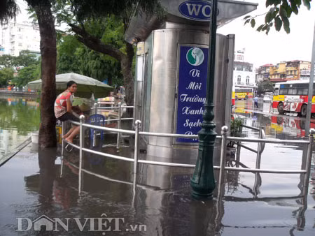 Sợ lội nước bẩn, người phụ nữ này phải ngồi co trên thành rào chắn chờ nước rút