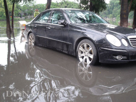 Dưới có hồ, còn phía trên lòng đường, vỉa hè cũng lại thành ao sau mưa Nước không thoát kịp xuống cống, ùn ùn đùn nước lên và chảy tràn xuống hồ Gươm Người đàn ông này bị mắc kẹt trên vỉa hè Nước lênh láng cả một đoạn dài phía đường Đinh Tiên Hoàng Có những chỗ ngập sâu đến nửa mét Bãi để xe ô tô ven hồ Gươm cũng bị ngập khá sâu Nước cống hòa nước mưa, ứ đọng, đen ngòm và kèm theo đó là mùi hôi thối nồng nặc Từng mảng váng bẩn cuộn lại theo dòng nước xoáy tràn xuống hồ Gươm Nước bẩn ào ào xối xuống lòng hồ