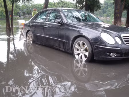 Dưới có hồ, còn phía trên lòng đường, vỉa hè cũng lại thành ao sau mưa Nước không thoát kịp xuống cống, ùn ùn đùn nước lên và chảy tràn xuống hồ Gươm Người đàn ông này bị mắc kẹt trên vỉa hè Nước lênh láng cả một đoạn dài phía đường Đinh Tiên Hoàng Có những chỗ ngập sâu đến nửa mét Bãi để xe ô tô ven hồ Gươm cũng bị ngập khá sâu Nước cống hòa nước mưa, ứ đọng, đen ngòm và kèm theo đó là mùi hôi thối nồng nặc Từng mảng váng bẩn cuộn lại theo dòng nước xoáy tràn xuống hồ Gươm Nước bẩn ào ào xối xuống lòng hồ