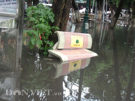 Dưới có hồ, còn phía trên lòng đường, vỉa hè cũng lại thành ao sau mưa Nước không thoát kịp xuống cống, ùn ùn đùn nước lên và chảy tràn xuống hồ Gươm Người đàn ông này bị mắc kẹt trên vỉa hè Nước lênh láng cả một đoạn dài phía đường Đinh Tiên Hoàng Có những chỗ ngập sâu đến nửa mét Bãi để xe ô tô ven hồ Gươm cũng bị ngập khá sâu Nước cống hòa nước mưa, ứ đọng, đen ngòm và kèm theo đó là mùi hôi thối nồng nặc Từng mảng váng bẩn cuộn lại theo dòng nước xoáy tràn xuống hồ Gươm Nước bẩn ào ào xối xuống lòng hồ