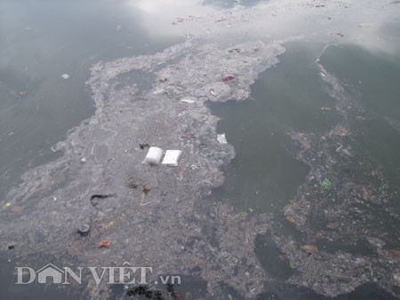 Dưới có hồ, còn phía trên lòng đường, vỉa hè cũng lại thành ao sau mưa Nước không thoát kịp xuống cống, ùn ùn đùn nước lên và chảy tràn xuống hồ Gươm Người đàn ông này bị mắc kẹt trên vỉa hè Nước lênh láng cả một đoạn dài phía đường Đinh Tiên Hoàng Có những chỗ ngập sâu đến nửa mét Bãi để xe ô tô ven hồ Gươm cũng bị ngập khá sâu Nước cống hòa nước mưa, ứ đọng, đen ngòm và kèm theo đó là mùi hôi thối nồng nặc Từng mảng váng bẩn cuộn lại theo dòng nước xoáy tràn xuống hồ Gươm Nước bẩn ào ào xối xuống lòng hồ