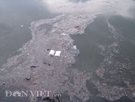 Dưới có hồ, còn phía trên lòng đường, vỉa hè cũng lại thành ao sau mưa Nước không thoát kịp xuống cống, ùn ùn đùn nước lên và chảy tràn xuống hồ Gươm Người đàn ông này bị mắc kẹt trên vỉa hè Nước lênh láng cả một đoạn dài phía đường Đinh Tiên Hoàng Có những chỗ ngập sâu đến nửa mét Bãi để xe ô tô ven hồ Gươm cũng bị ngập khá sâu Nước cống hòa nước mưa, ứ đọng, đen ngòm và kèm theo đó là mùi hôi thối nồng nặc Từng mảng váng bẩn cuộn lại theo dòng nước xoáy tràn xuống hồ Gươm Nước bẩn ào ào xối xuống lòng hồ