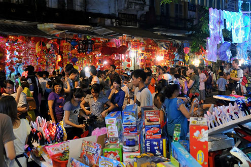 Tối 10/9, chợ đồ chơi Hàng Mã, Hàng Lược, Lương Văn Can, Hàng Đường... đông nghẹt người dạo chơi, tham quan, mua sắm. Trước đêm trung thu 2 ngày, dòng người chen lấn mua đồ chơi. Hai cô gái trẻ đứng giữa đoàn người qua lại ngắm nghía mình qua chiếc gương. Các cửa hàng bày hàng tràn lan ra đường làm thu hẹp không gian thưởng ngoạn của người chơi. Giải pháp cho bé ngồi trên vai là cách chống chen bẹp người của nhiều ông bố. Nạn bắn súng bong bóng xà phòng vào người đi đường vẫn tiếp diễn. Ôtô len vào nơi này cũng gặp khó khăn. Tài xế phải thò đầu ra nhờ mọi người tránh đường. Nhiều hàng bày bán lấn chiếm lòng lề đường khiến lực lượng bảo vệ phải liên tục làm việc. Và đội quân bán rong lại cầm ghế, bê hàng chạy sang chỗ khác. Những chiếc mặt nạ quái đản lại xuất hiện. Tối 10/9, chợ đồ chơi Hàng Mã, Hàng Lược, Lương Văn Can, Hàng Đường... đông nghẹt người dạo chơi, tham quan, mua sắm. Trước đêm trung thu 2 ngày, dòng người chen lấn mua đồ chơi. Hai cô gái trẻ đứng giữa đoàn người qua lại ngắm nghía mình qua chiếc gương. Các cửa hàng bày hàng tràn lan ra đường làm thu hẹp không gian thưởng ngoạn của người chơi. Giải pháp cho bé ngồi trên vai là cách chống chen bẹp người của nhiều ông bố. Nạn bắn súng bong bóng xà phòng vào người đi đường vẫn tiếp diễn. Ôtô len vào nơi này cũng gặp khó khăn. Tài xế phải thò đầu ra nhờ mọi người tránh đường. Nhiều hàng bày bán lấn chiếm lòng lề đường khiến lực lượng bảo vệ phải liên tục làm việc. Và đội quân bán rong lại cầm ghế, bê hàng chạy sang chỗ khác. Những chiếc mặt nạ quái đản lại xuất hiện.