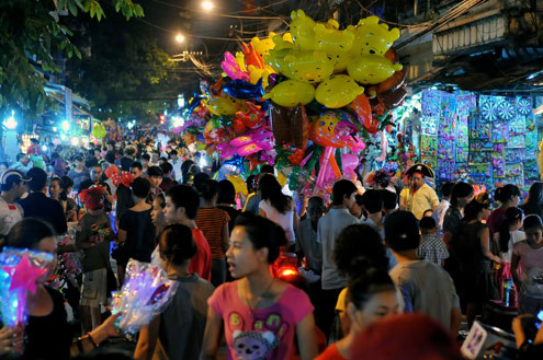 Tối 10/9, chợ đồ chơi Hàng Mã, Hàng Lược, Lương Văn Can, Hàng Đường... đông nghẹt người dạo chơi, tham quan, mua sắm. Trước đêm trung thu 2 ngày, dòng người chen lấn mua đồ chơi. Hai cô gái trẻ đứng giữa đoàn người qua lại ngắm nghía mình qua chiếc gương. Các cửa hàng bày hàng tràn lan ra đường làm thu hẹp không gian thưởng ngoạn của người chơi. Giải pháp cho bé ngồi trên vai là cách chống chen bẹp người của nhiều ông bố. Nạn bắn súng bong bóng xà phòng vào người đi đường vẫn tiếp diễn. Ôtô len vào nơi này cũng gặp khó khăn. Tài xế phải thò đầu ra nhờ mọi người tránh đường. Nhiều hàng bày bán lấn chiếm lòng lề đường khiến lực lượng bảo vệ phải liên tục làm việc. Và đội quân bán rong lại cầm ghế, bê hàng chạy sang chỗ khác. Những chiếc mặt nạ quái đản lại xuất hiện. Tối 10/9, chợ đồ chơi Hàng Mã, Hàng Lược, Lương Văn Can, Hàng Đường... đông nghẹt người dạo chơi, tham quan, mua sắm. Trước đêm trung thu 2 ngày, dòng người chen lấn mua đồ chơi. Hai cô gái trẻ đứng giữa đoàn người qua lại ngắm nghía mình qua chiếc gương. Các cửa hàng bày hàng tràn lan ra đường làm thu hẹp không gian thưởng ngoạn của người chơi. Giải pháp cho bé ngồi trên vai là cách chống chen bẹp người của nhiều ông bố. Nạn bắn súng bong bóng xà phòng vào người đi đường vẫn tiếp diễn. Ôtô len vào nơi này cũng gặp khó khăn. Tài xế phải thò đầu ra nhờ mọi người tránh đường. Nhiều hàng bày bán lấn chiếm lòng lề đường khiến lực lượng bảo vệ phải liên tục làm việc. Và đội quân bán rong lại cầm ghế, bê hàng chạy sang chỗ khác. Những chiếc mặt nạ quái đản lại xuất hiện.