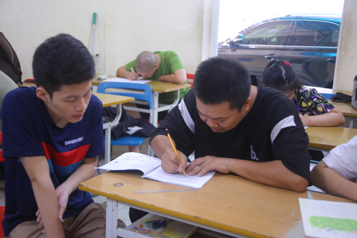 Anh Lê Đình Thắng hướng dẫn em Nguyễn Nhật Long học bài. (Ảnh: Thu Thủy) GDVN_FM5A0757.JPG