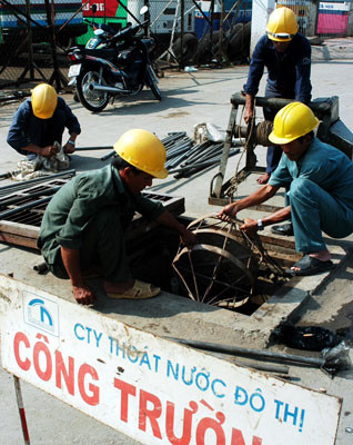 Công nhân Công ty Thoát nước đô thị thông cống chống ngập. Ảnh: THÁI BẰNG Công nhân Công ty Thoát nước đô thị thông cống chống ngập. Ảnh: THÁI BẰNG