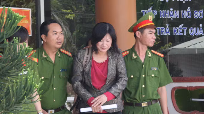 Công an dẫn giải bị can Trần Thị Thật rời Sở Y tế Tiền Giang - Ảnh: Trường Giang