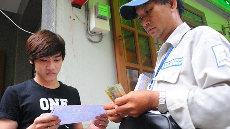 Nhân viên thu tiền điện tại nhà người dân ở P.5, Q.Gò Vấp, TP.HCM chiều 15-11 - Ảnh: T.T.D.