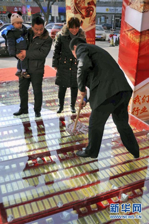 Nhân viên lau phần kính bên trên để số vàng được hiện rõ hơn. Để đảm bảo an toàn cho số vàng, cửa hàng đã thuê một lực lượng bảo an dày đặc túc trực 24/24. Ảnh: Xinhua