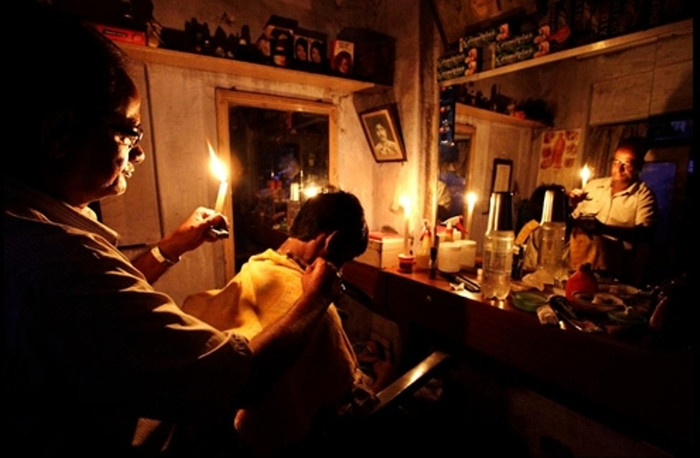 Một người thợ Ấn Độ phải thắp nến để cắt tóc cho khách hàng. Cuộc khủng hoảng năng lượng tại đây đã bùng phát sau khi ba đường dây điện nước này bị hỏng, khiến 620 triệu người dân phải chịu cảnh tối tăm trong nhiều ngày. (Ảnh: AP) Một người thợ Ấn Độ phải thắp nến để cắt tóc cho khách hàng. Cuộc khủng hoảng năng lượng tại đây đã bùng phát sau khi ba đường dây điện nước này bị hỏng, khiến 620 triệu người dân phải chịu cảnh tối tăm trong nhiều ngày. (Ảnh: AP)