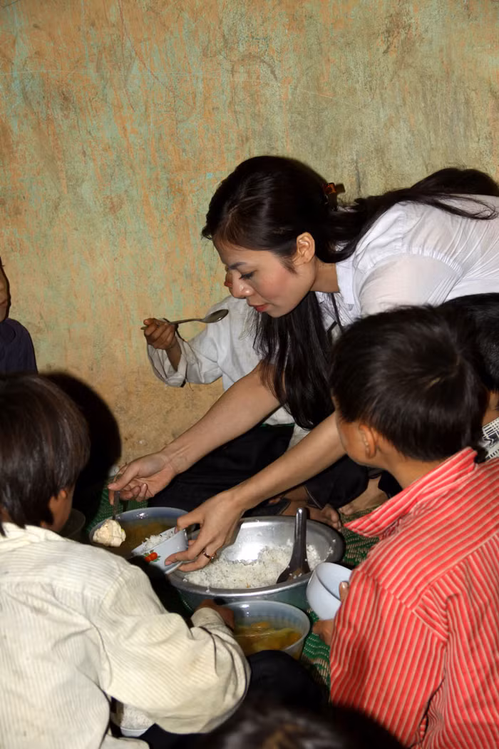 Tự tay xới cho các em những bát cơm và gắp những miếng thịt.