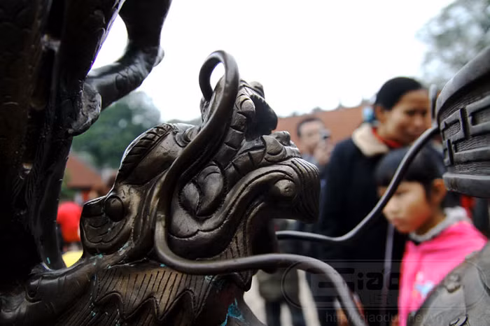 và một con rồng chầu bên trái của chiếc đỉnh đồng khổng lồ.