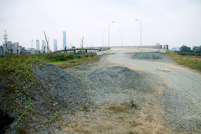 Đường dẫn vào cầu vượt Phù Đổng ngổn ngang đất đá, cỏ hoang dại mọc dầy đặc.